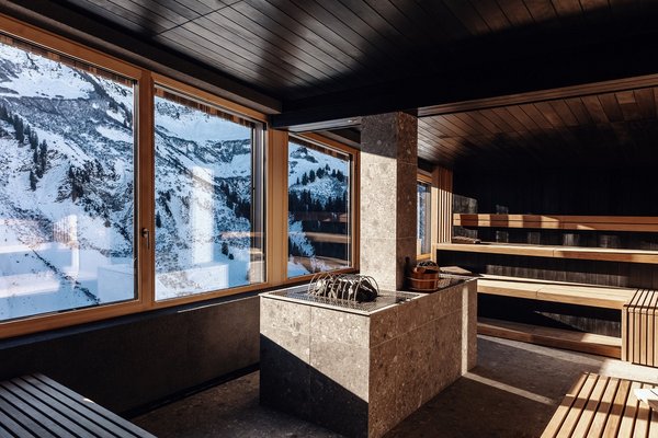 Moderne Panoramasauna mit großer Fensterfront und Ausblick auf die verschneiten Berge