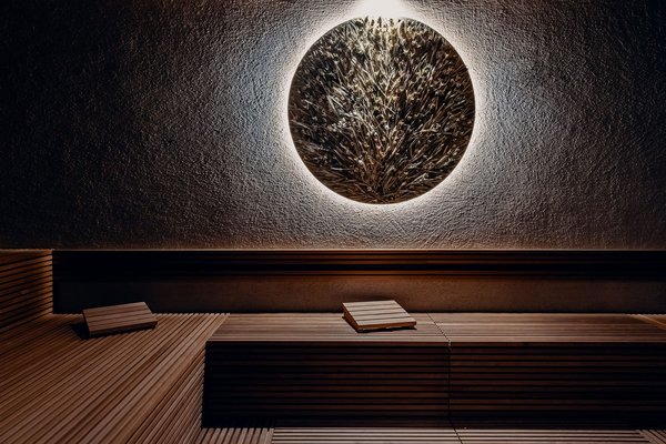 Große Wandlampe mit Strohschmuck in einem Saunaraum mit Liegeflächen aus Holz
